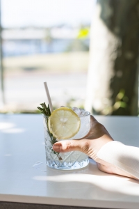 A diner at the Tradewinds Restaurant holds a glass of gin and tonic, garnished with a lemon slice and rosemary sprig
